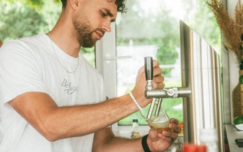 Mann steht hinter der Bar und befüllt ein Bierglas.
